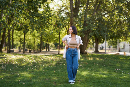 Happy asian girl walking in park, feeling freedom and joy, walking outdoors on sunny dayの写真素材