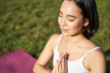 Portrait of young mindful woman, practice yoga, exercising, inhale and exhale on fresh air in park,...