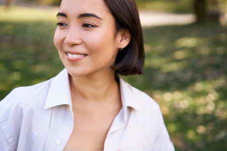 Beautiful young asian girl smiling, laughing and walking along park, enjoying summer sunny dayの写真素材