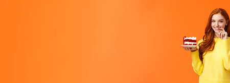 Girl wants share her piece cake with loved one. Romantic silly cute girlfriend brink piece dessert to eat together, smiling and touching lip flirty, eating junk food during diet, orange backgroundの写真素材