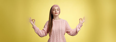 No stress. Pretty young female student not worry, releasing negative emotions during yoga training session standing in lotus pose, breathing smiling relieved happy, showing mudra sign feeling relaxedの写真素材