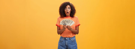 Woman shocked finding lots of cash in safe. Portrait of surprised speechless good-looking...