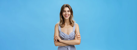 Happy charismatic adult european woman with cute gap teeth smiling broadly crossing hands against...