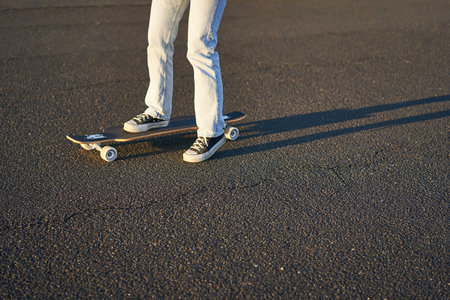 Cropped shot of legs on longboard. Skater girl riding her skateboard on street. Female teenager on cruiserの写真素材