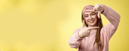 Charming outgoing, happy girl smiling cheerful, making frame of fingers looking through it excited...