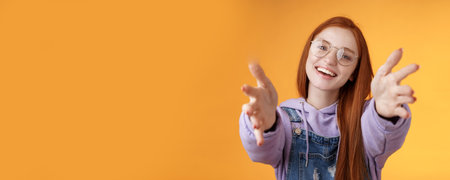 Come here let hold. Attractive silly friendly happy smiling redhead woman stretch arms camera grab product wanna tight friendship hugs grinning embracing cuddling besties, orange backgroundの写真素材