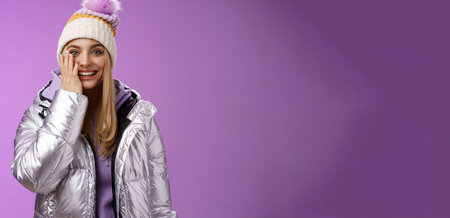 Delighted amused tender blond girlfriend fool around look playful playing snowballs touch cheek astonished feel dream come true enjoying vacation winter holidays boyfriend, standing purple backgroundの写真素材