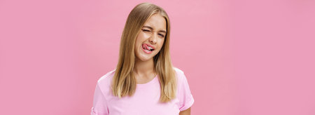 Playful flirty attractive young girl with fair straight hair in t-shirt winking at camera smiling...