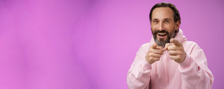 Funny amused carefree happy adult handsome man pranking friend fool around pointing camera index...