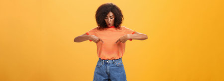 Portrait of worried questioned and surprised african american female with curly hairstyle looking...