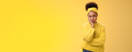 Offended gloomy grumpy pouting young african-american girlfriend feel irritated jealous frowning bothered sulking look away insulted unwilling talk somebody lean hand head standing yellow backgroundの写真素材
