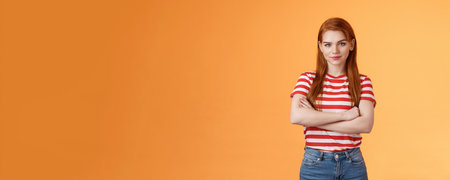 Go on try me. Confident cool redhead daring woman cross arms professional pose, smiling determined motivated win, look assertive and assured own powers, stand orange backgroundの写真素材