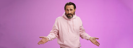Bothered confused mature adult bearded man grey hair in pink hoodie arguing look pissed offended...