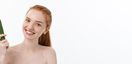 Cheerful happy beautiful girl with cucumber on her hand - isolated on whiteの写真素材
