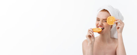 Great food for a healthy lifestyle. Beautiful young shirtless woman holding piece of orange standing against white background.の写真素材