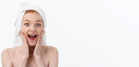 Surprised Beautiful Young Woman After Bath with A Towel On Her Head Isolated On white Background. Skin Care And Spa Theme.の写真素材