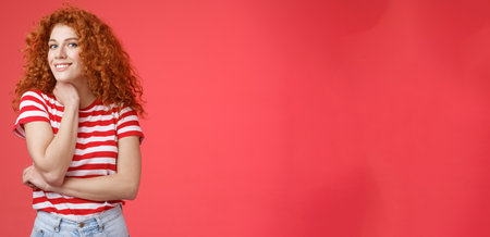 Cheerful lively cute tender redhead curly girl romantic summer mood pondering what present girlfriend happy pride month silly smiling touch face-line look curious camera red backgroundの写真素材