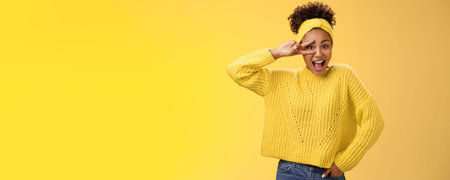 Energetic charming millennial african-american female student in yellow sweater headband show...