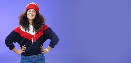 Confident ad energized cute european woman with curly hairstyle in warm beanie and stylish...