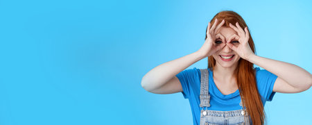Playful cheerful redhead european woman, long nature red hairstyle, show okay finger glasses look...