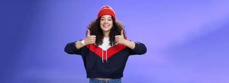 Girl totally agrees recommends cool place showing thumbs-up and smiling excited with happy grin...