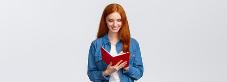 Creative and talented good-looking female college student prepare schedule for tomorrow classes, writing in diary, taking notes in fancy notebook, standing white backgroundの写真素材