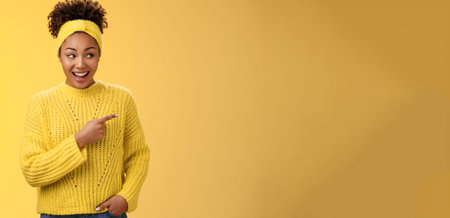 Astonished cute feminine modern african-american woman gossiping silly laughing drop jaw laughing surprised pointing right discuss during conversation interesting rumour place, yellow backgroundの写真素材