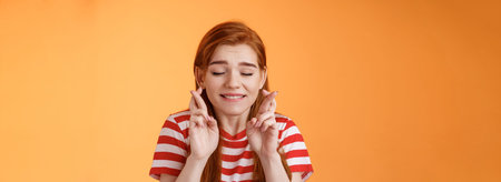 Close-up dreamy cute tender ginger girl make wish, cross fingers good luck closed eyes bite lip...