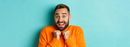 Close-up of startled man gasping and pressing hands to chest, staring at camera shocked, standing...