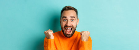 Image of handsome relieved man feeling satisfaction, rejoicing of winning or achievement, making...