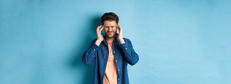 Man feeling sick, touching head and grimacing from painful migraine, having headache or feel dizzy,...