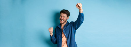 Lucky man celebrating victory, cheering and shouting yes with joy, raising hand up like champion,...