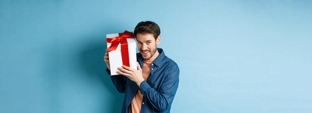 Valentines day. Romantic boyfriend showing gift box for lover, celebrating anniversary, standing...