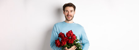 Romantic boyfriend bring beautiful bouquet of red roses on valentines day, having date with girlfriend, saying I love you, standing passionate on white backgroundの写真素材