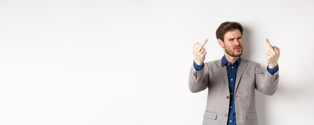 Rude businessman in suit showing middle finger, fuck you gesture, look annoyed and pissed-off, standing on white backgroundの写真素材