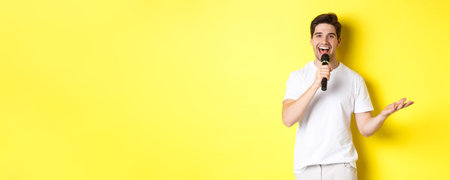 Happy man entertainer performing, talking in microphone, making speech or stand-up show, standing...