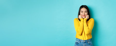Beauty and fashion concept. Beautiful asian woman blushing and smiling, looking at something cute...