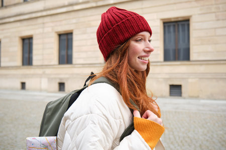 Tourism and travelling. Young redhead woman smiling, tourist walking with backpack around city...