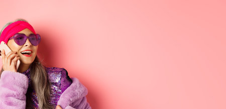 Fashion. Close-up of fashionable asian senior woman in sunglasses and disco outfit talking on phone,...