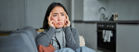 Sick korean woman coughing and feeling unwell, grimacing, has influenza, cought cold or flu, staying...