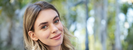 Vertical portrait of beautiful adult woman, sitting in blue collar shirt outdoors, smiling and looking cute at cameraの写真素材
