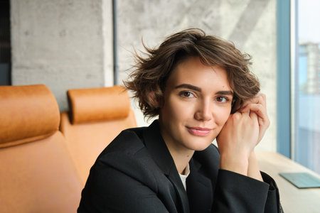 Portrait of saleswoman working on laptop, sitting in office and preparing for meeting with a client