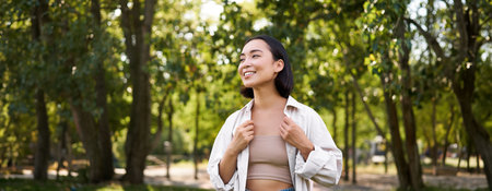 Image of korean girl walking in park, smiling while having a mindful walk in woodsの写真素材