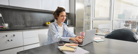 Portrait of hardworking woman studying from home, typing on laptop keyboard and smiling, working on...