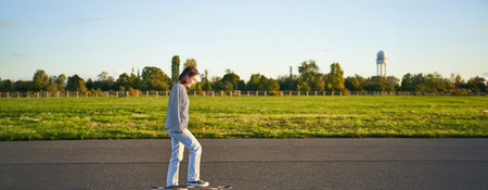 Hobbies and lifestyle. Young woman riding skateboard. Skater girl enjoying cruise on longboard on...