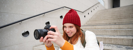 Urban people and lifestyle. Happy redhead woman takes photos, holding professional digital camera, photographing on streetsの写真素材