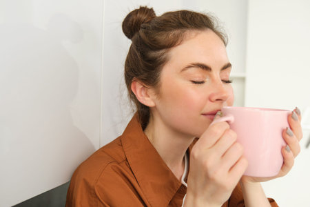 Close up portrait of beautiful brunette woman with cup of coffee, drinking aromatic beverage from...