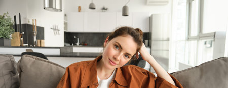 Lifestyle concept. Young smiling brunette woman, sitting at home on sofa, resting on couch, looking...
