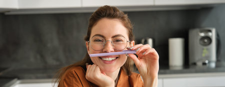Close up portrait of funny, happy young woman, student sitting in kitchen, learning on remote and...