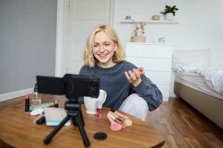 Portrait of young teenage girl in her room, recording a vlog, daily lifestyle video for social media, internet influencer advertising product online, talking to the camera, sitting on the floorの写真素材